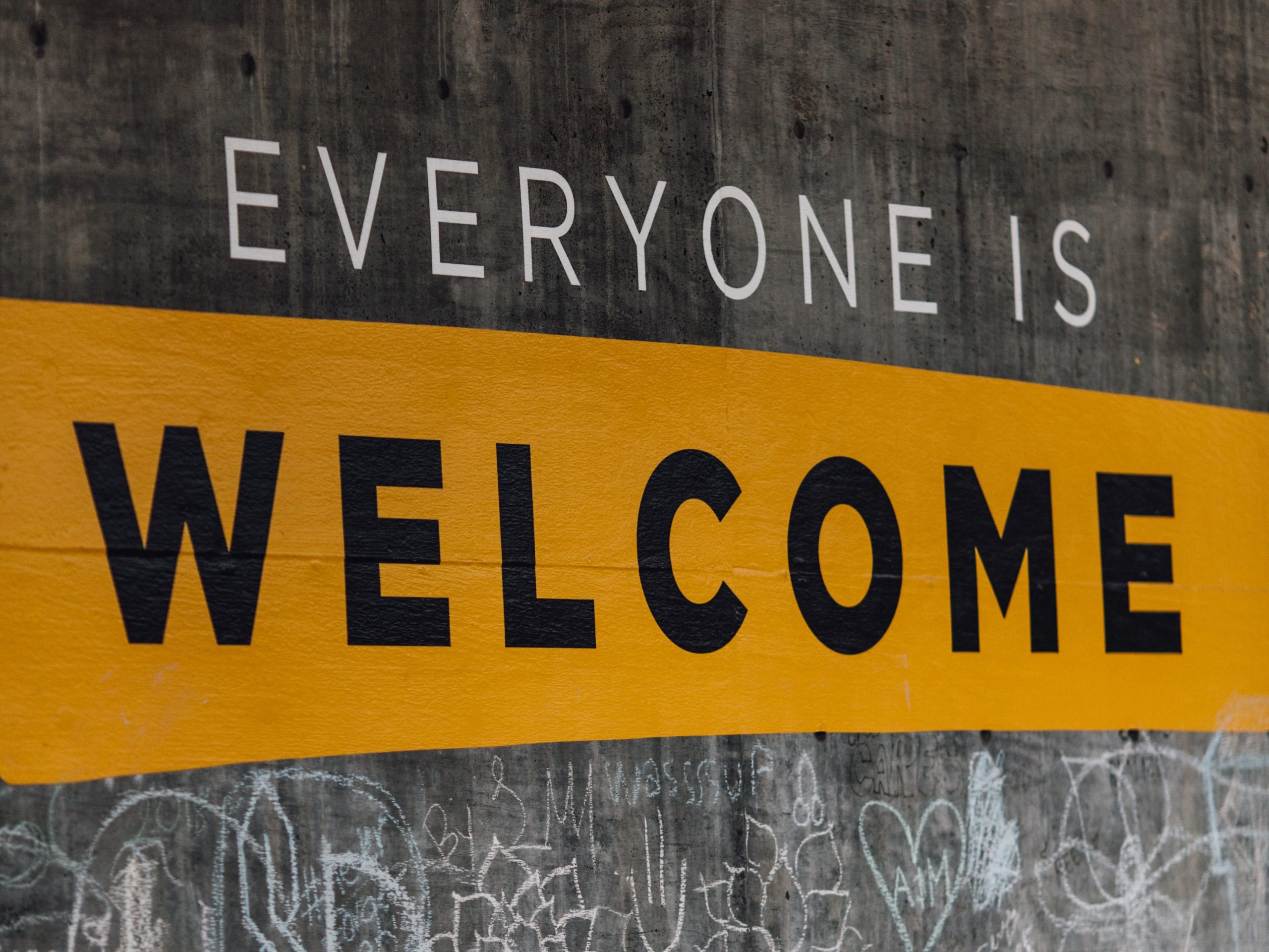 Everyone Is Welcome sign on concrete wall